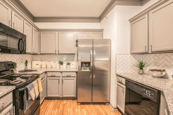 A modern kitchen with a stainless steel refrigerator and wooden floors.