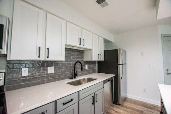 A kitchen with black appliances and white cabinets.