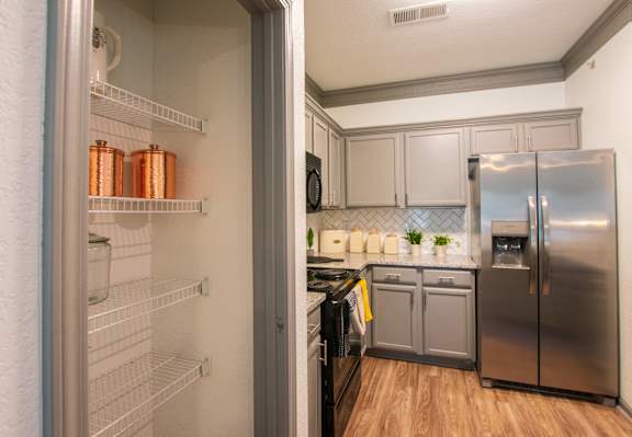 A kitchen with a refrigerator and an open fridge.