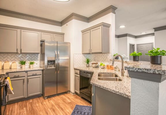 A kitchen with a stainless steel refrigerator and a sink.