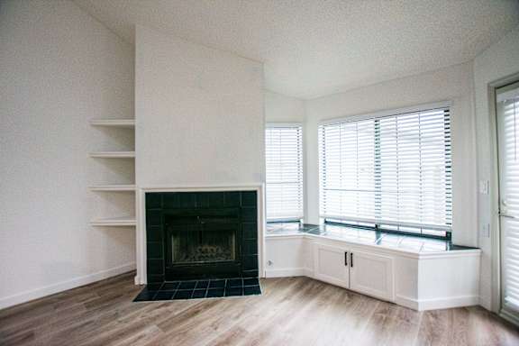 A white room with a fireplace and wooden floors.