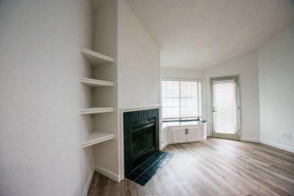 A living room with a fireplace and built in shelves.