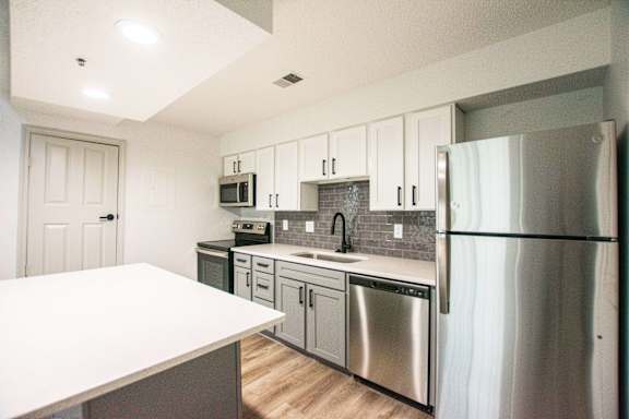 A kitchen with a white counter top and stainless steel appliances.