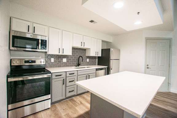 A kitchen with a white counter top and stainless steel appliances.