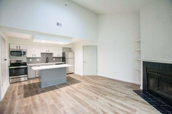 A modern kitchen with wooden floors and a fireplace.