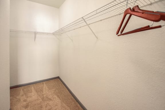 A red clamp is on a wire shelf in a white room.