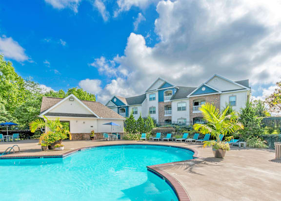 A large swimming pool in front of a multi-story apartment building.