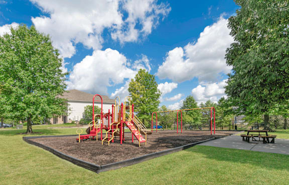 A playground with a red swing set and a yellow slide.
