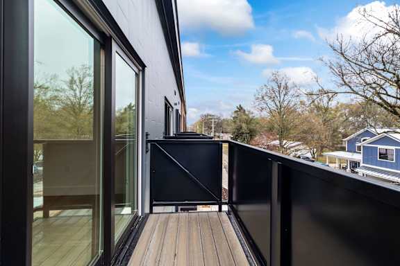 A modern deck with a glass door leading to a balcony.