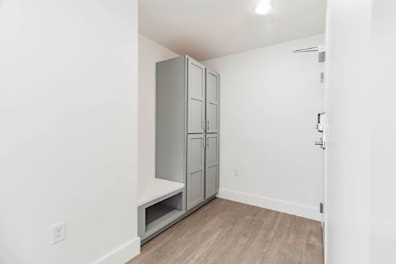 A white room with a grey wardrobe and a shelf underneath it.