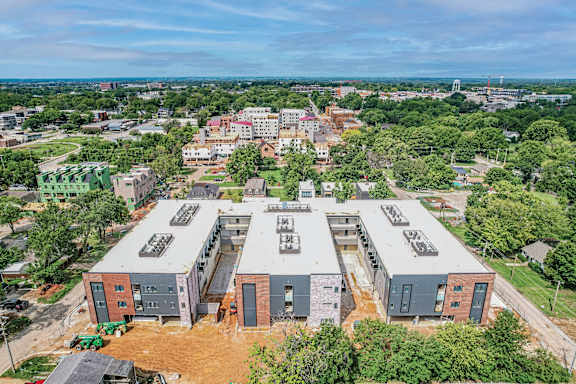 A large building complex with a flat roof and a parking lot in front.