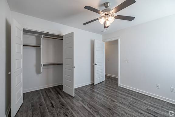 A room with a ceiling fan and a closet with a sliding door.