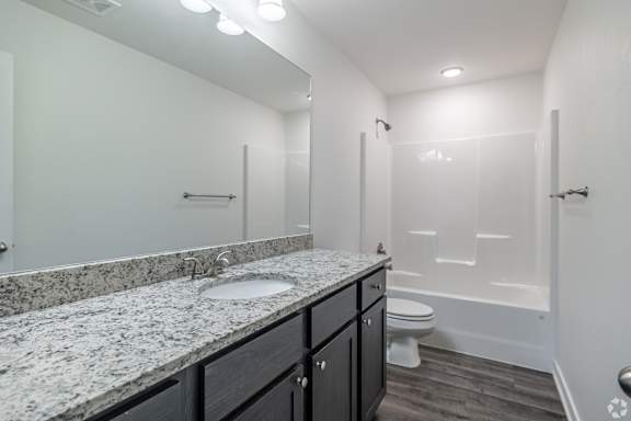 A bathroom with a marble countertop and a walk-in shower.