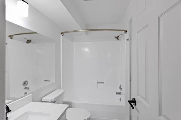 A white bathroom with a toilet, sink, and shower.