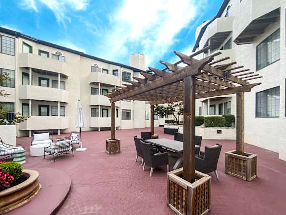 A patio with a table and chairs under a pergola.