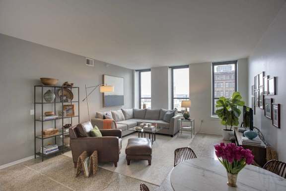 A living room with a couch, chairs, and a table with a vase of flowers on it.