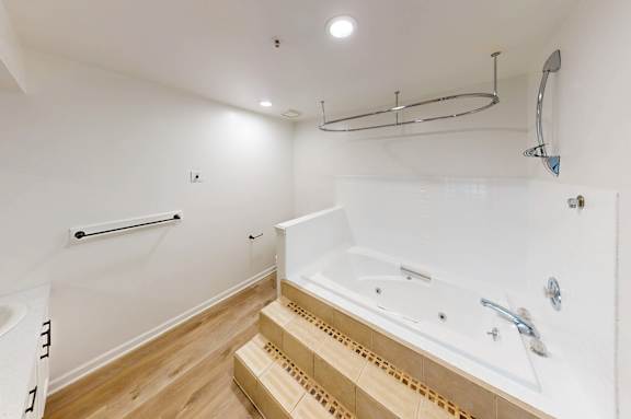 A white bathroom with a tub and a towel rack.