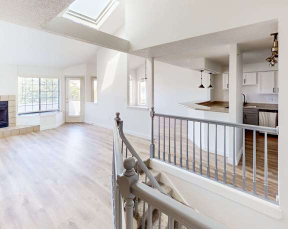 A spacious living room with a fireplace and a staircase leading to the upper floor.