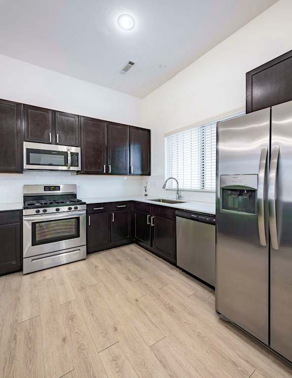 A kitchen with a stainless steel refrigerator, oven, and microwave.