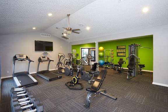 A gym with a variety of equipment including treadmills, weights, and exercise machines.