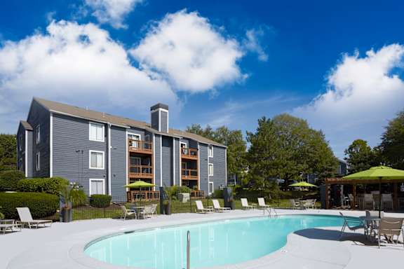 A swimming pool in front of a grey apartment building.