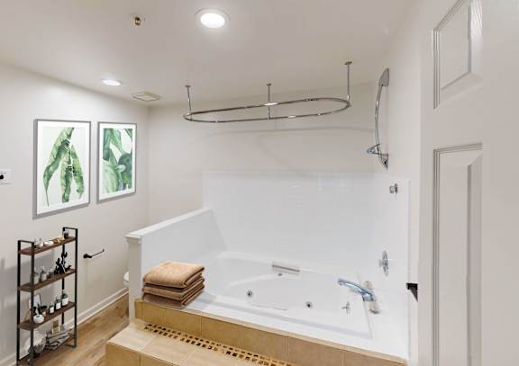 A white bathroom with a large tub and a towel on top of it.