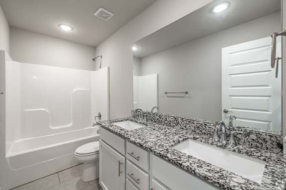 a bathroom with two sinks and a toilet and a bath tub