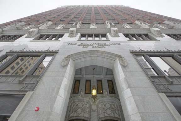A tall building with a red sign on the top and a large entrance below.