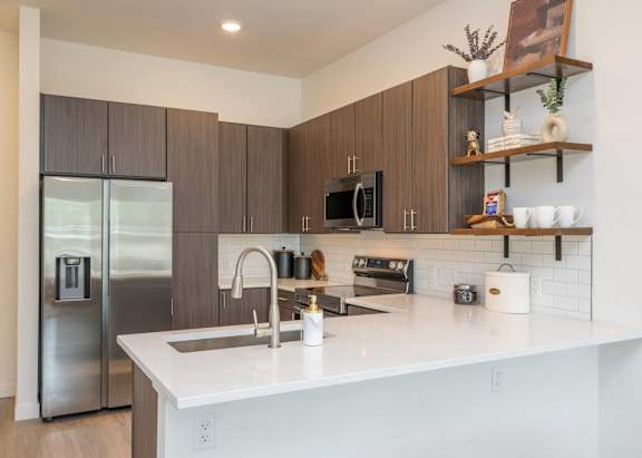 A modern kitchen with a white countertop and stainless steel appliances.