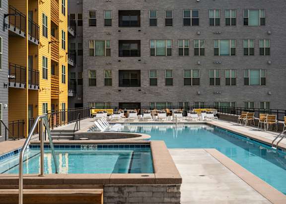 A swimming pool with a diving board and chairs around it.