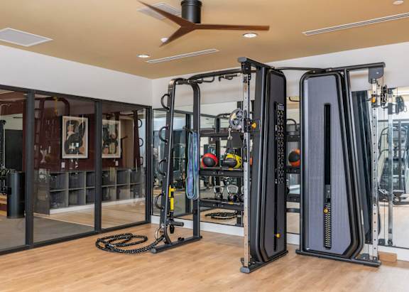 A gym with a variety of equipment including a treadmill, a weight machine, and a cable machine.