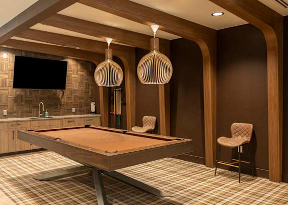 A pool table in a room with wooden walls and a chair.