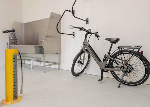 A bicycle is parked next to a yellow pole with a metal structure in the background.
