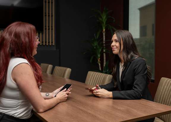 Two women sitting at a table, one holding a phone.