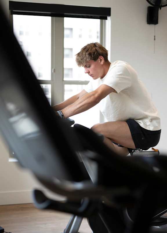 A man is working out on a stationary bike in a room.