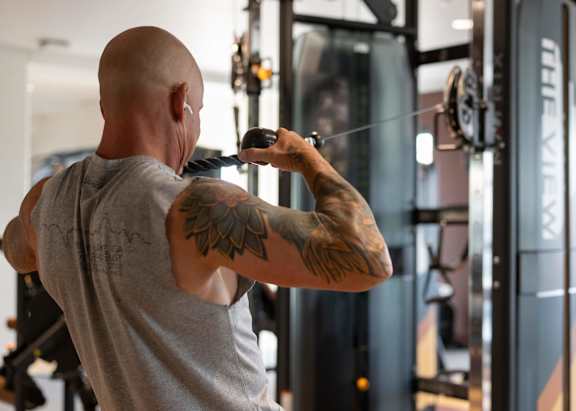 A man with a tattoo on his arm is working out in a gym.