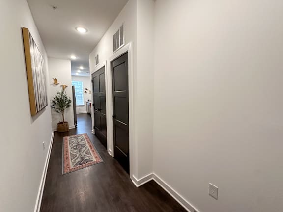 A hallway with a rug and a painting on the wall.