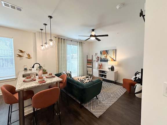 A dining room with a table set for two and a green couch.