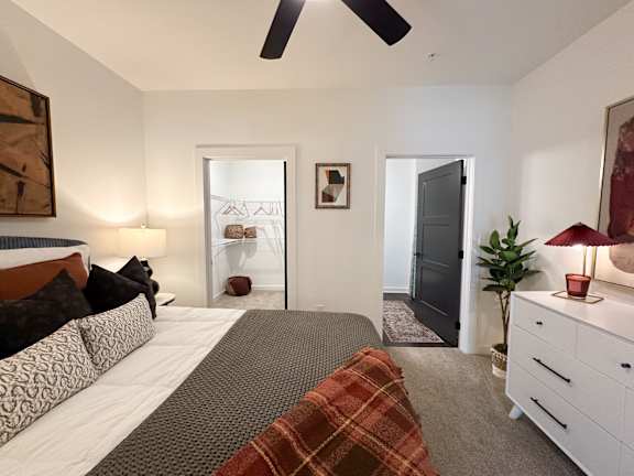 A bedroom with a bed, dresser, and ceiling fan.