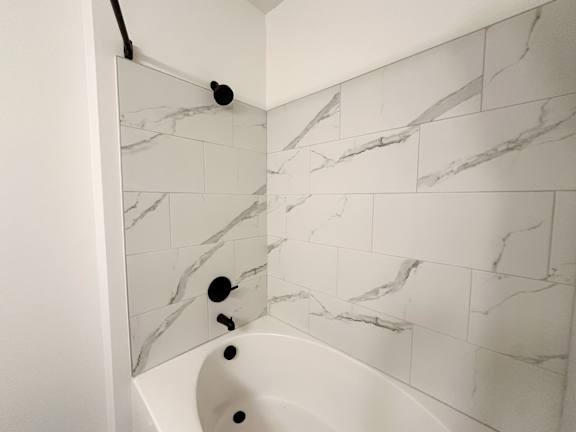 A white bathroom with a marble tile wall.