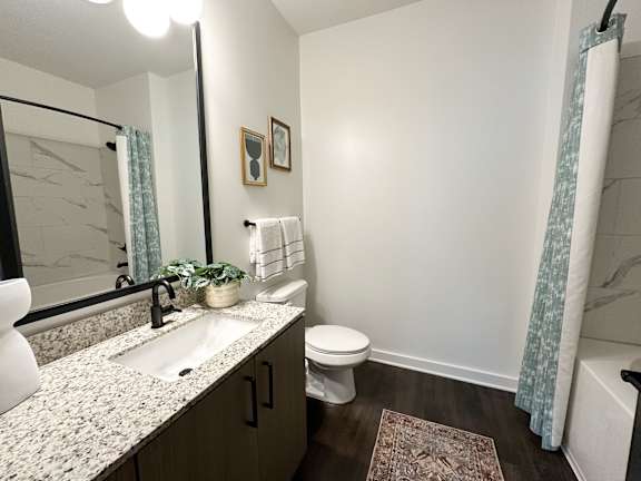 A bathroom with a sink, toilet, and mirror.