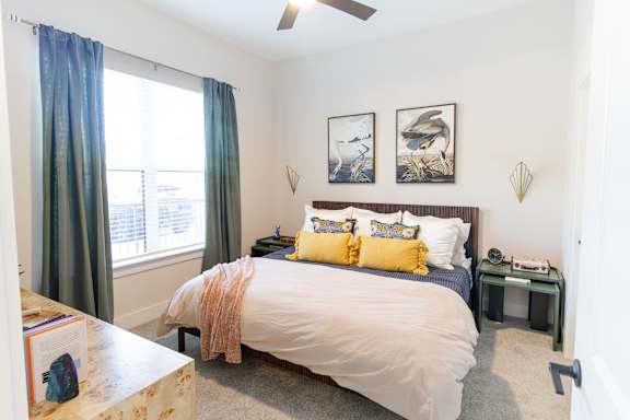 A bedroom with a bed, nightstand, and window.
