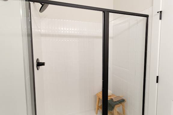 A glass shower door with a black handle.