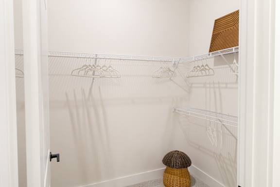 A white closet with a brown stool.