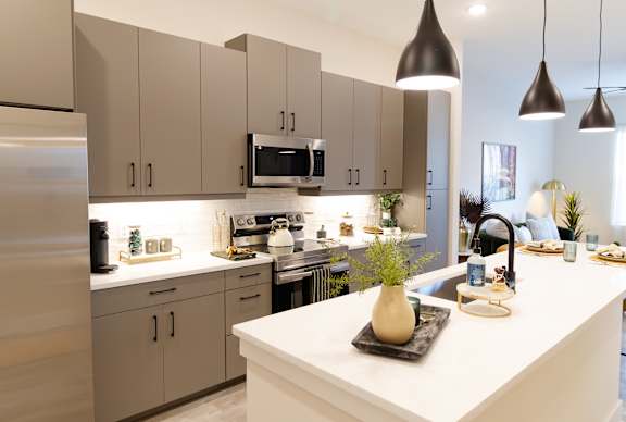 A modern kitchen with a white countertop and beige cabinets.