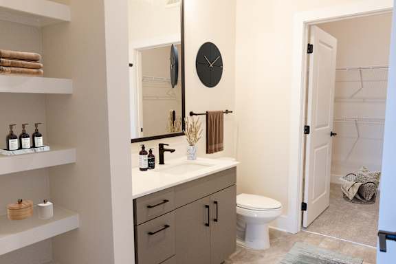 A bathroom with a toilet, sink, mirror, and shelves.at Riverside Apartments, Tennessee, 37406