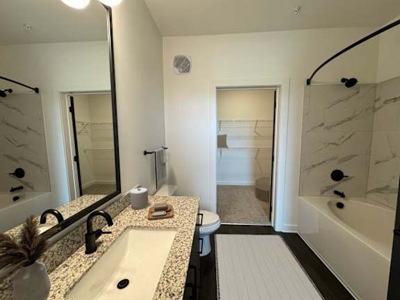 A bathroom with a marble countertop and a white bathtub.