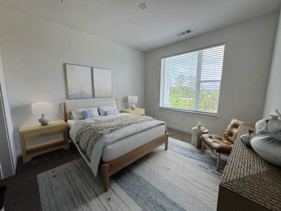 A bedroom with a large bed, a chair, and a window.