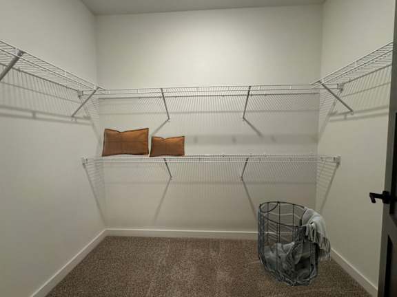 A small, empty room with a wire shelf and a laundry basket on the floor.