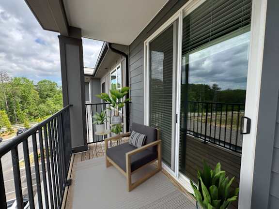 A balcony with a bench and potted plants.